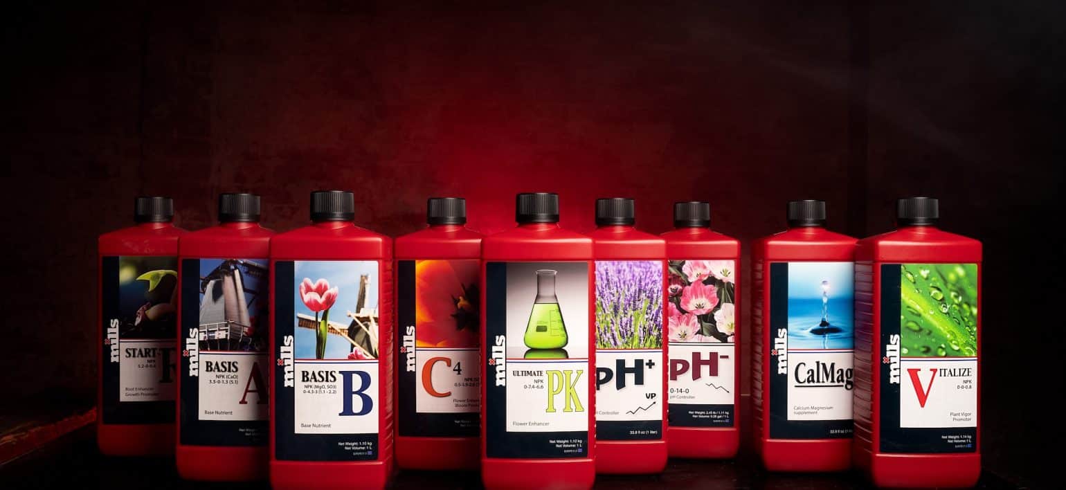 Five red bottles of Mills Nutrients: Start R, Basis A, Basis B, C4, and Ultimate PK displayed on a dark reflective surface