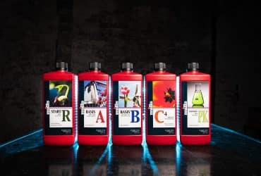 Five red bottles of Mills Nutrients angled left on a dark table with glowing blue reflections, featuring Start R, Basis A, Basis B, C4, and Ultimate PK.